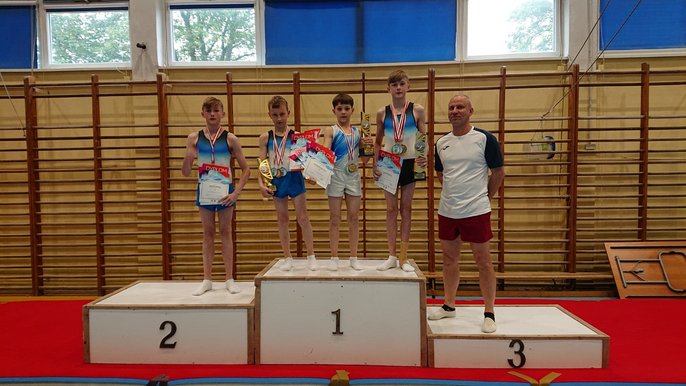 Chłopcy w wieku szkolnym wraz z trenerem pozują na podium trzymając medale i dyplomy. Chłopcy w wieku szkolnym wraz z trenerem pozują na podium trzymając medale i dyplomy. - Chłopcy w wieku szkolnym wraz z trenerem pozują na podium trzymając medale i dyplomy.
